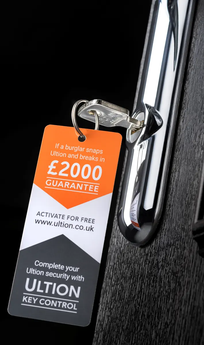 Ultion key and chrome handle on a black composite door with the orange 2000 pound guarantee tag