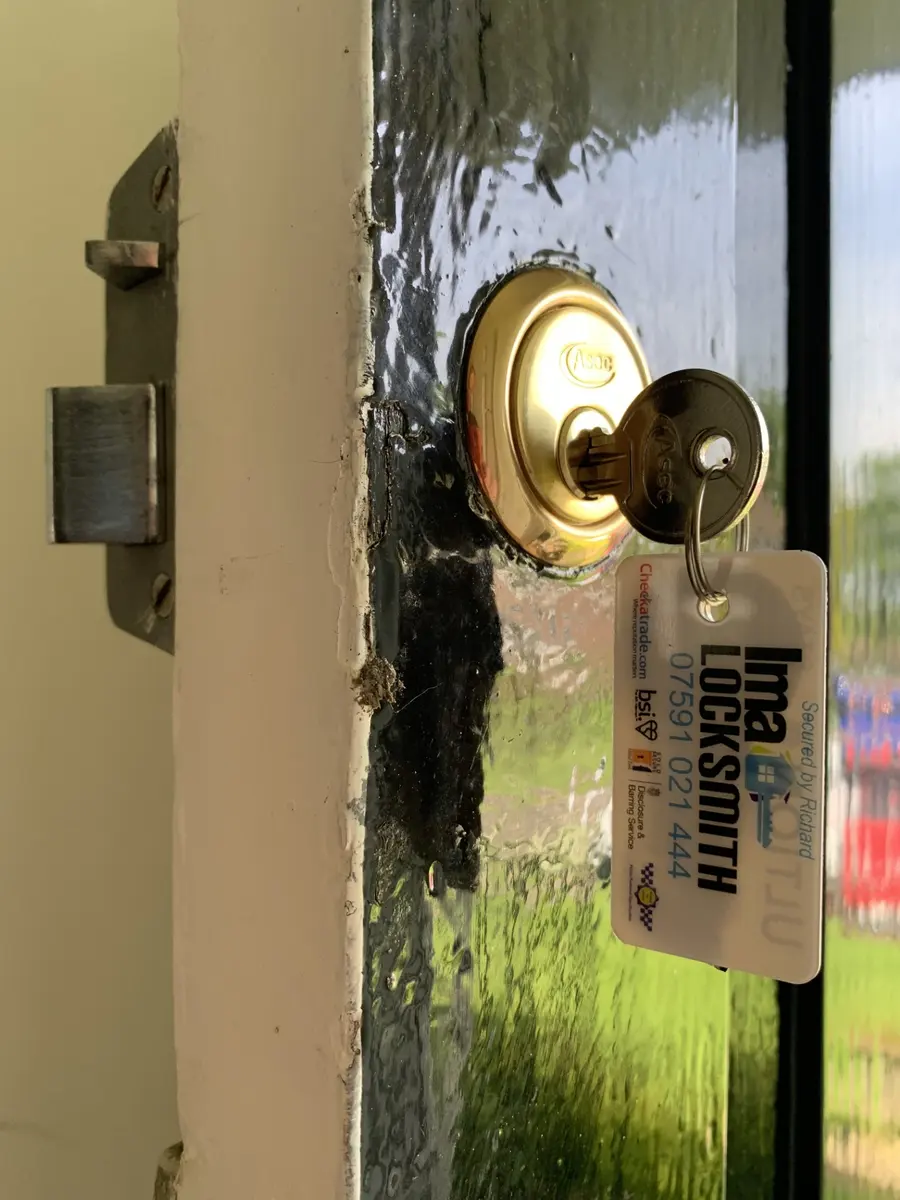 New brass Asec rim cylinder fitted to a black glazed timber door, IMA Locksmith tag on the key