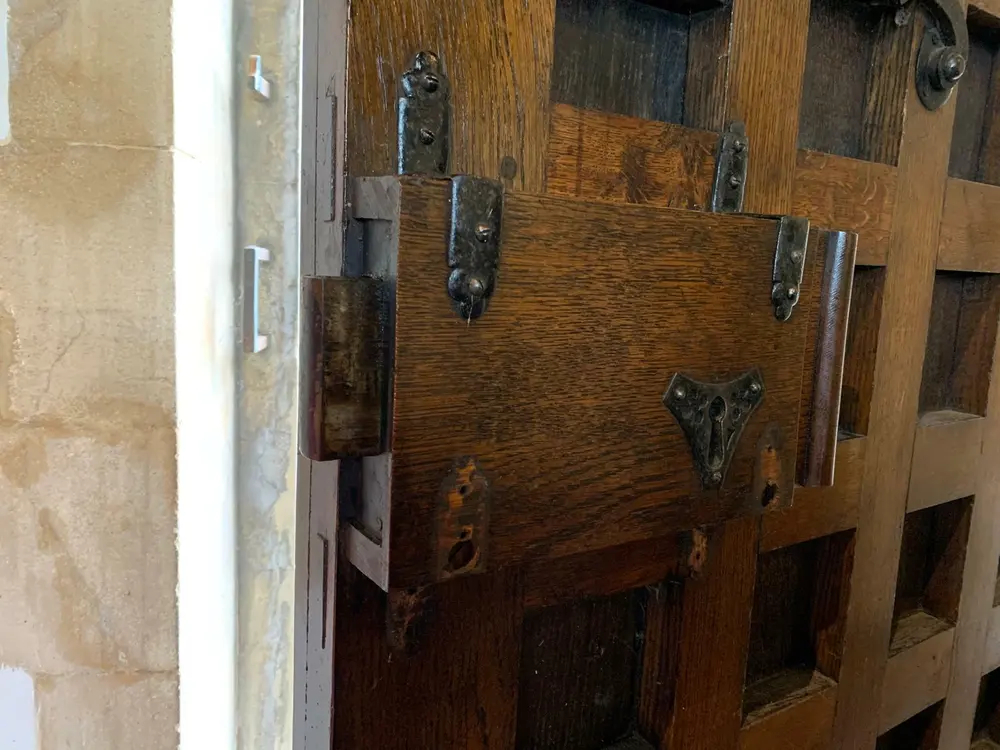 Antique timber lock case with decorative ironwork on a heavy studded oak door