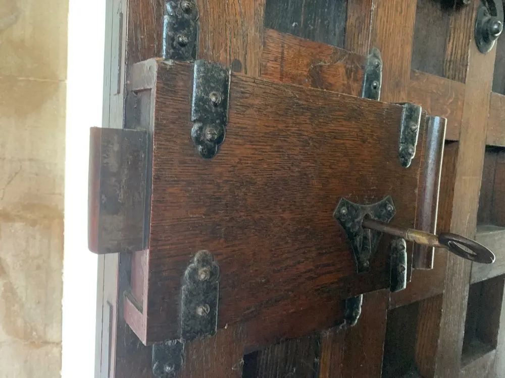 Traditional wooden rim lock box with iron strapwork and original key on an old oak lattice door