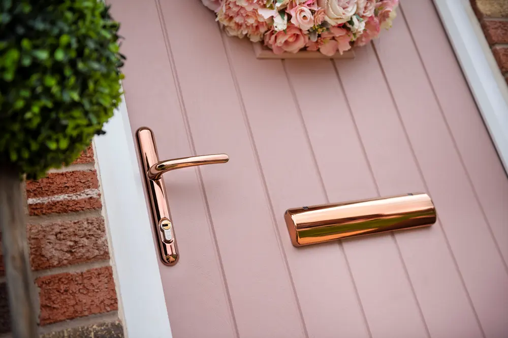 Rose gold lever handle, euro cylinder and matching letterbox on a pink composite front door