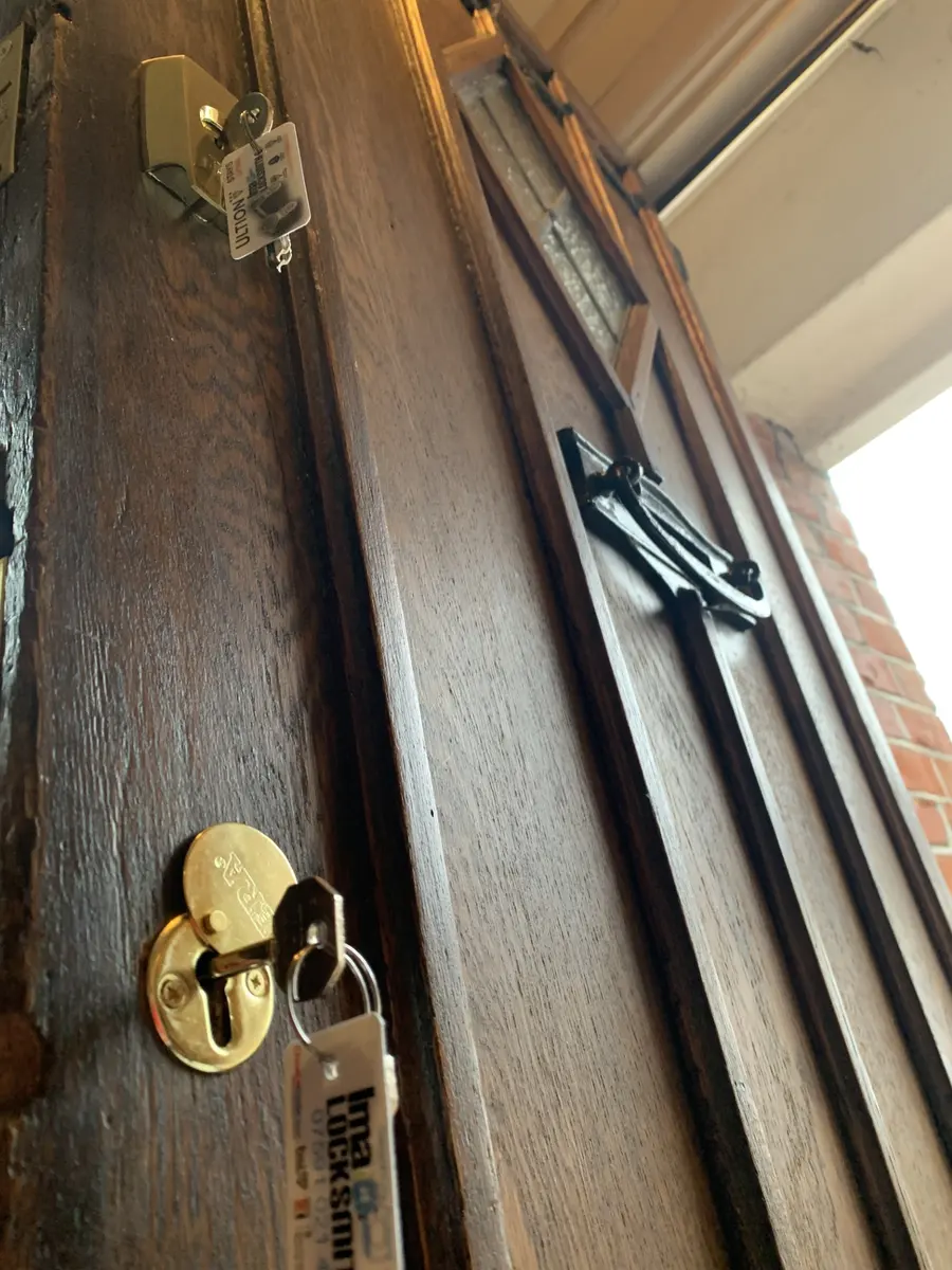 Brass night latch and escutcheon fitted to a dark oak front door, Ima Locksmith tags on both keys