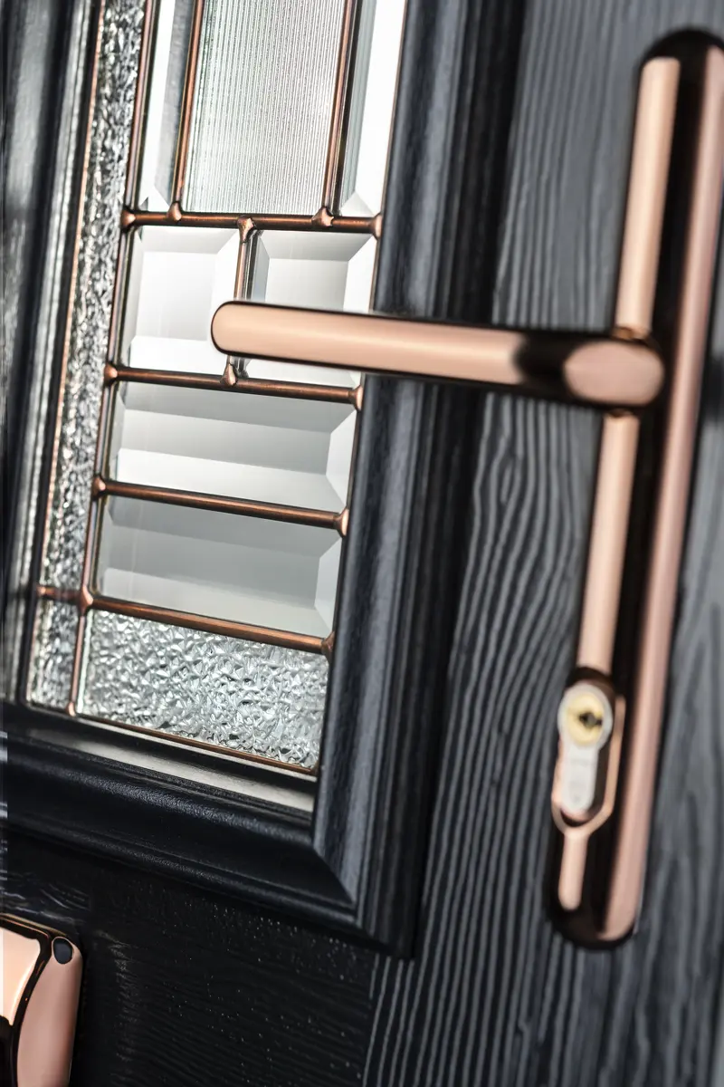 Copper lever handle and euro cylinder on a black woodgrain composite door with bevelled glazing