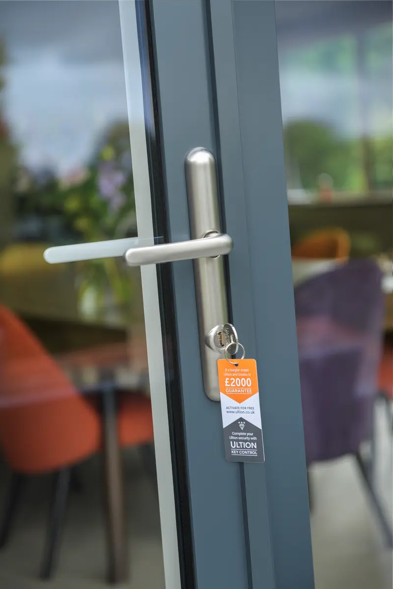 Ultion anti-snap cylinder with £2000 guarantee tag on an anthracite grey aluminium door with stainless handle