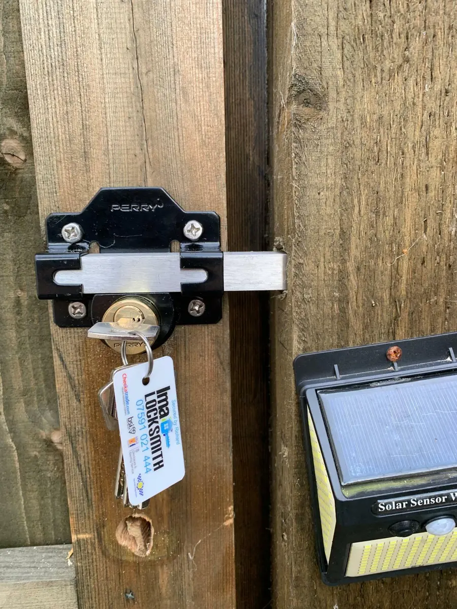 Black Perry long throw gate lock with key in the cylinder, Ima Locksmith tag on the keyring