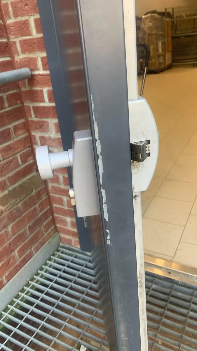 Silver knob and surface mounted latch fitted to a grey steel commercial door