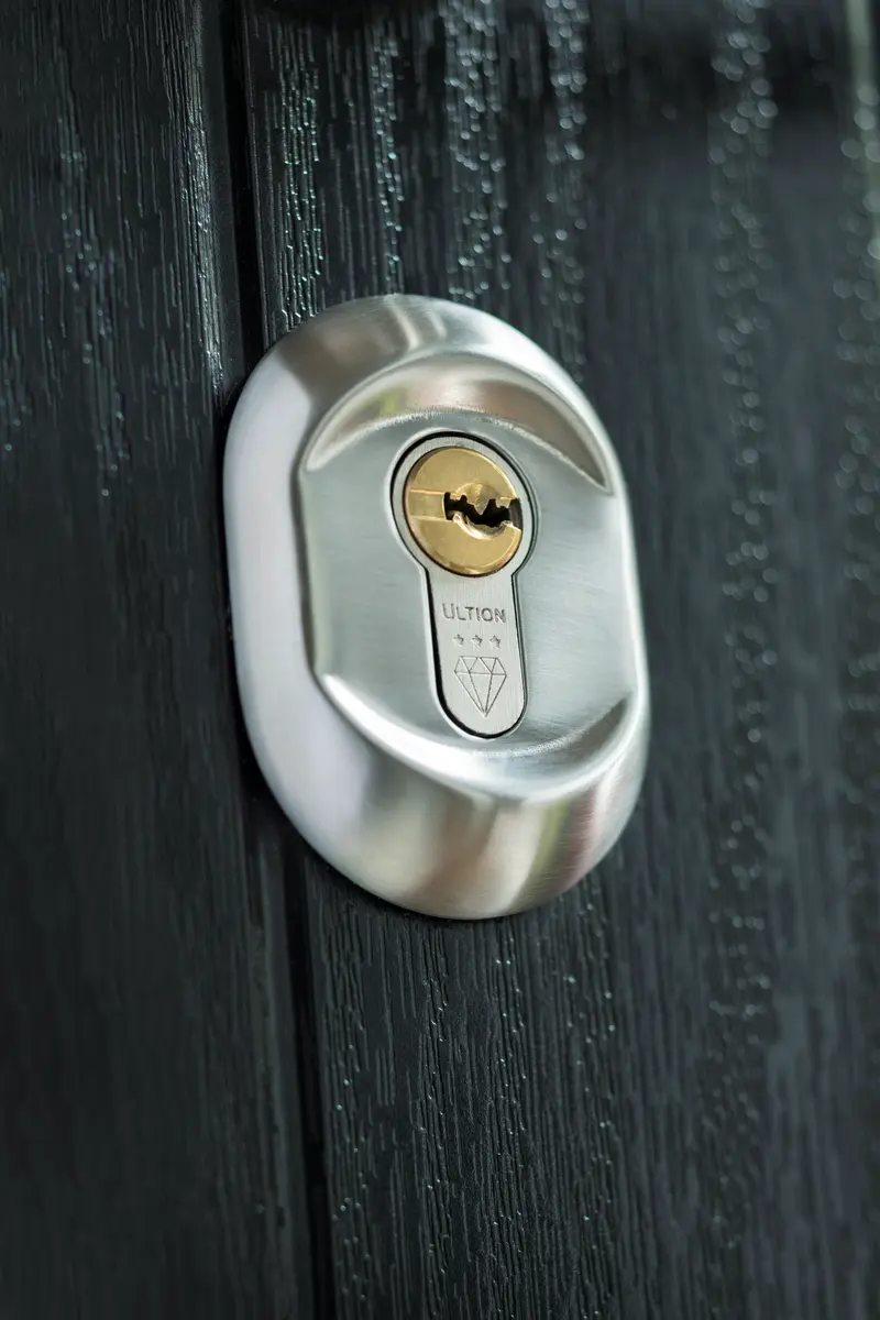 Ultion three star anti-snap euro cylinder with brass keyway in a black woodgrain composite door