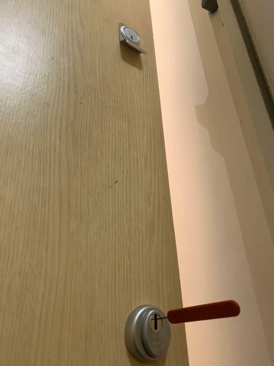 Oak effect flat entrance door fitted with a deadlock and high security rim cylinder, red key inserted
