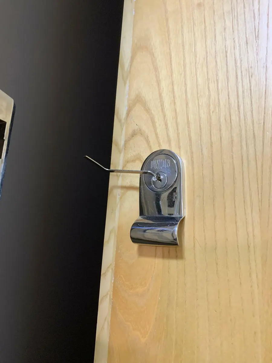 Chrome Union rim cylinder on a light timber door with lock picks inserted during non destructive entry