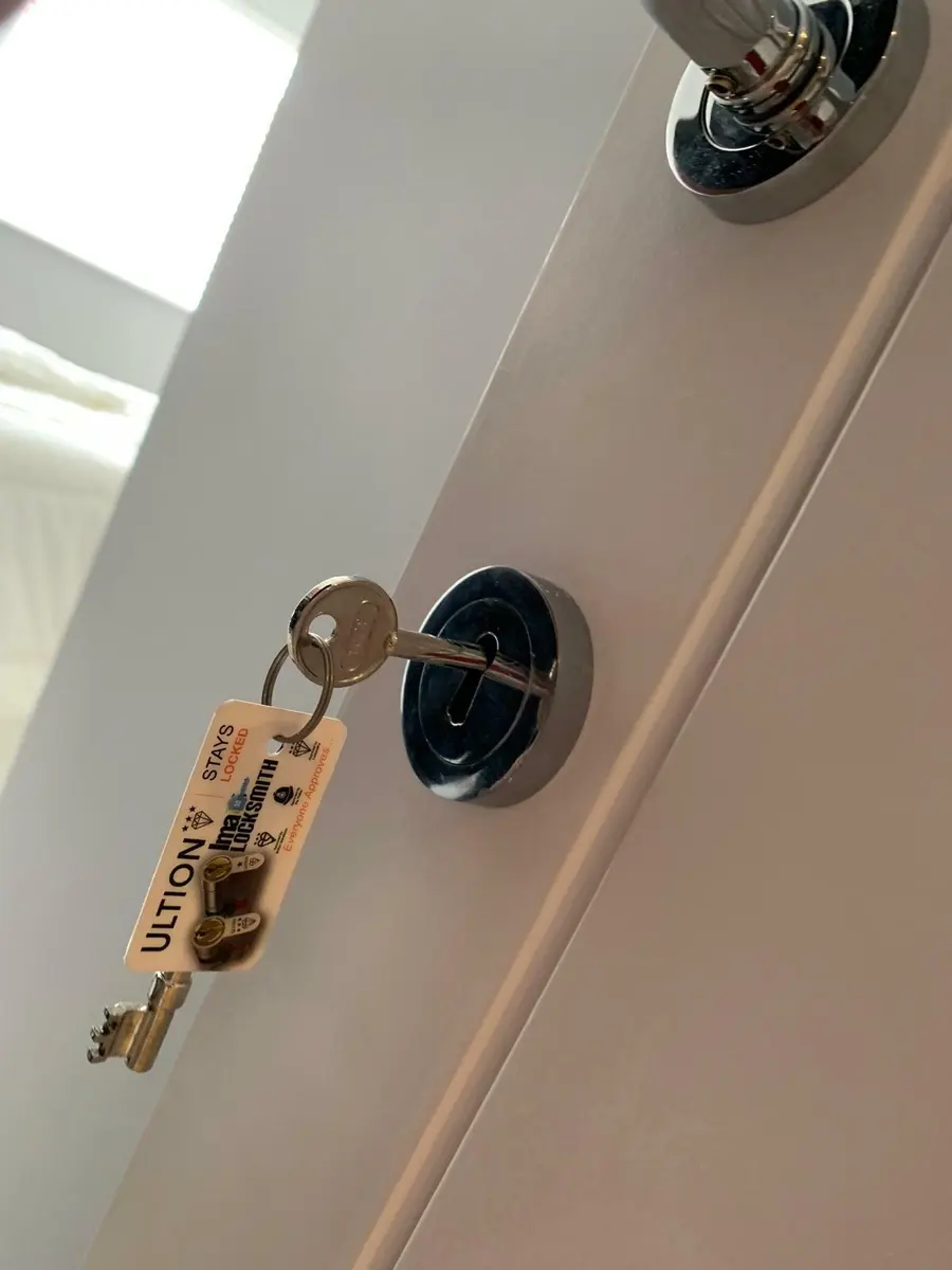 Mortice key in a chrome escutcheon on a white internal door, Ultion and Ima Locksmith tag attached