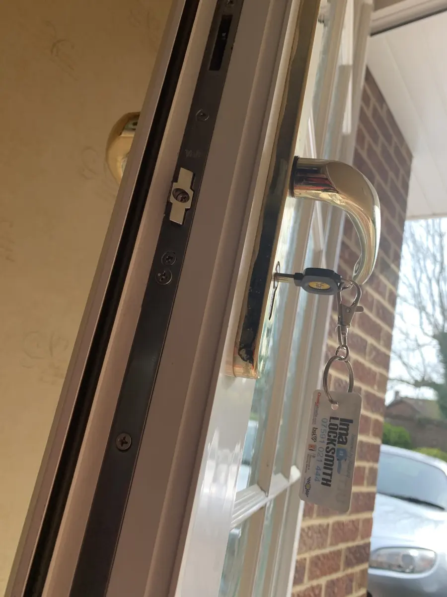 Yale multipoint lock strip on an open uPVC door edge with gold handle and Ima Locksmith keyring