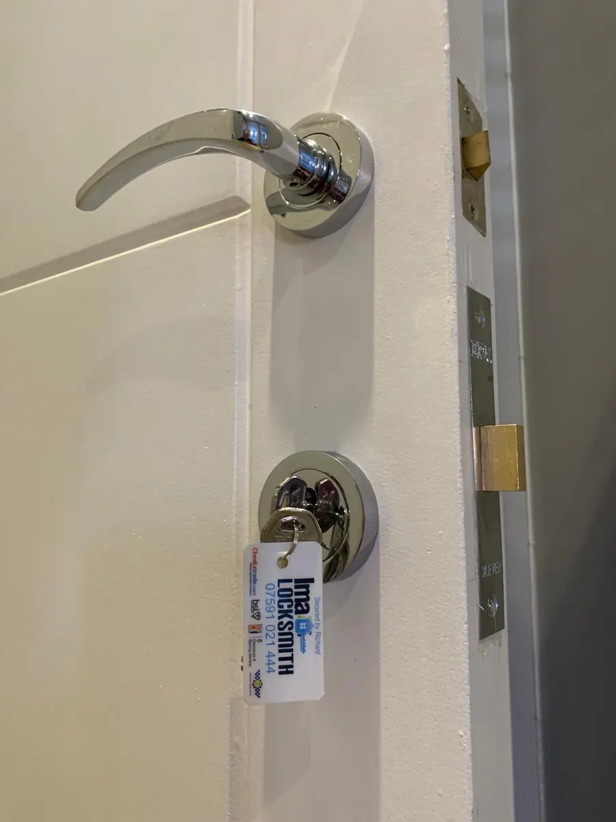 Chrome lever handle and mortice deadlock keys on a white internal door with Ima Locksmith tag