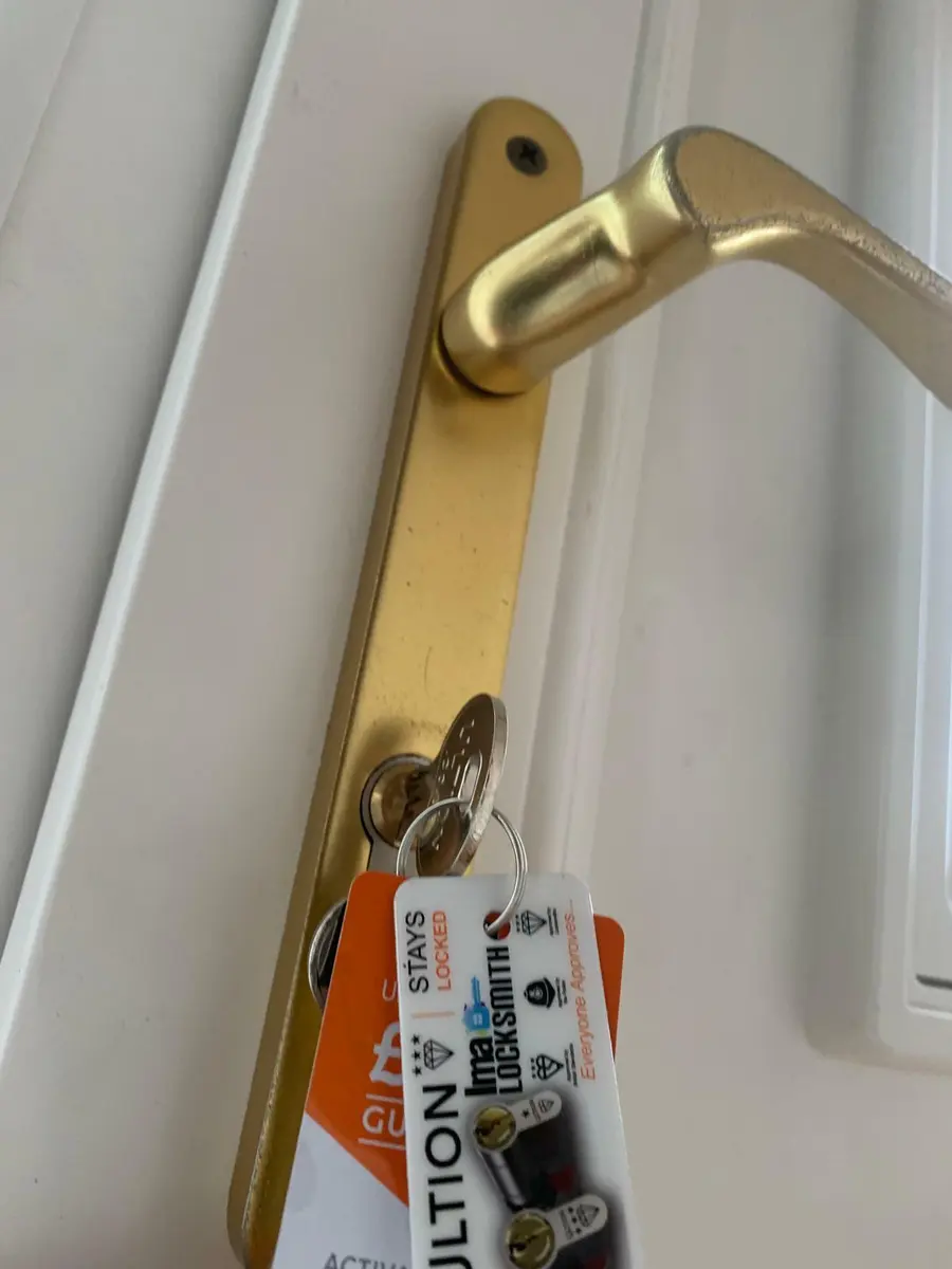 Gold multipoint door handle on a white uPVC door with new Ultion key and tags