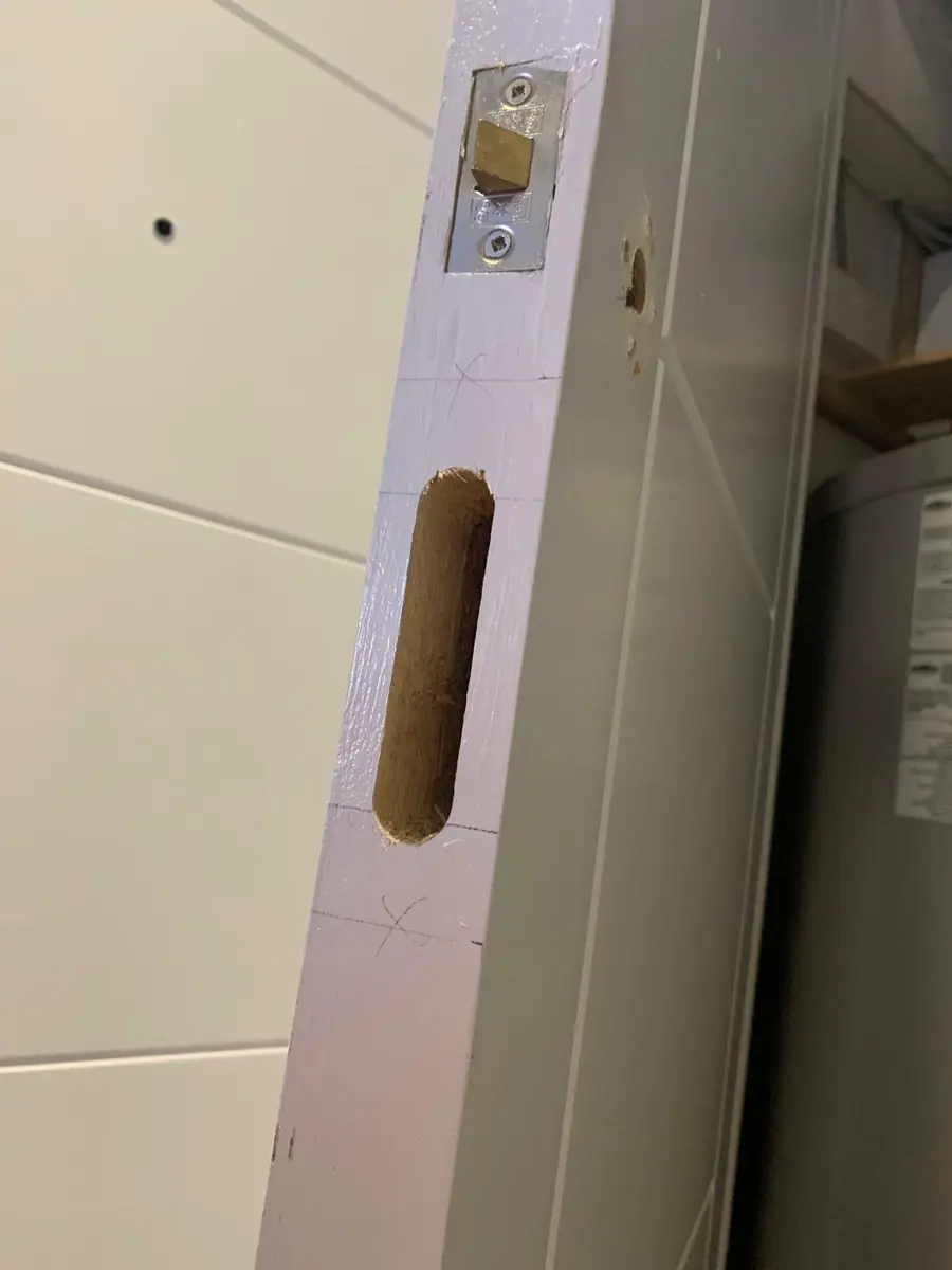 Freshly cut mortice slot and new latch in a painted door edge during lock fitting